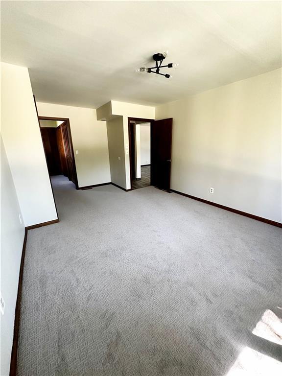 empty room featuring baseboards and light carpet