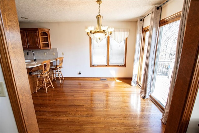 22513 E 33rd St S, Blue Springs, MO 64015 - dining area with visible vents, baseboards, an inviting chandelier, wood finished floors, and a textured ceiling