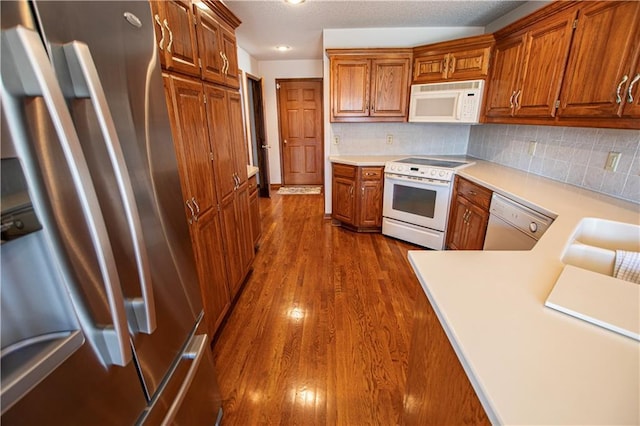 22513 E 33rd St S, Blue Springs, MO 64015 - kitchen featuring white appliances, dark wood-style floors, brown cabinets, light countertops, and tasteful backsplash