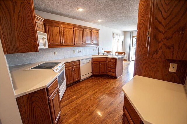 22513 E 33rd St S, Blue Springs, MO 64015 - kitchen with tasteful backsplash, dark wood-type flooring, brown cabinets, a peninsula, and white appliances