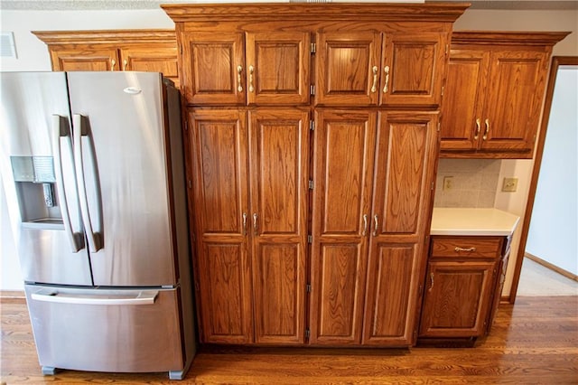22513 E 33rd St S, Blue Springs, MO 64015 - kitchen featuring tasteful backsplash, stainless steel fridge with ice dispenser, light countertops, wood finished floors, and brown cabinetry