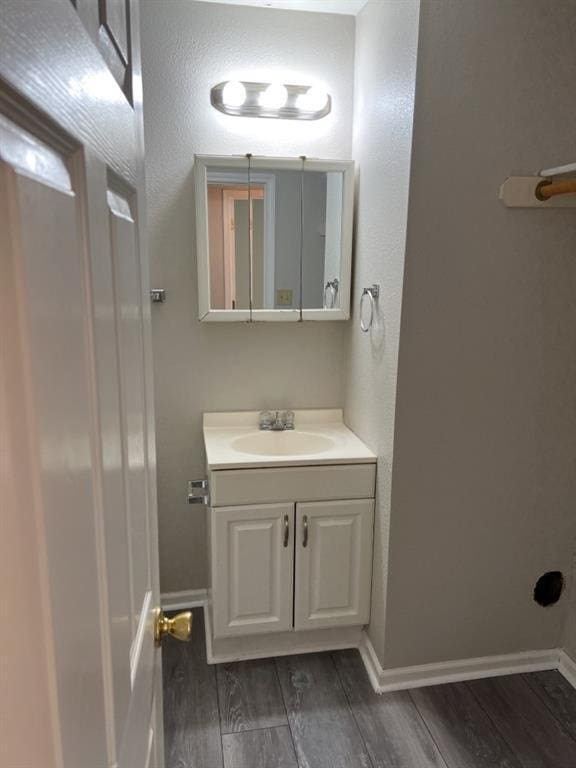 bathroom featuring baseboards, wood finished floors, and vanity