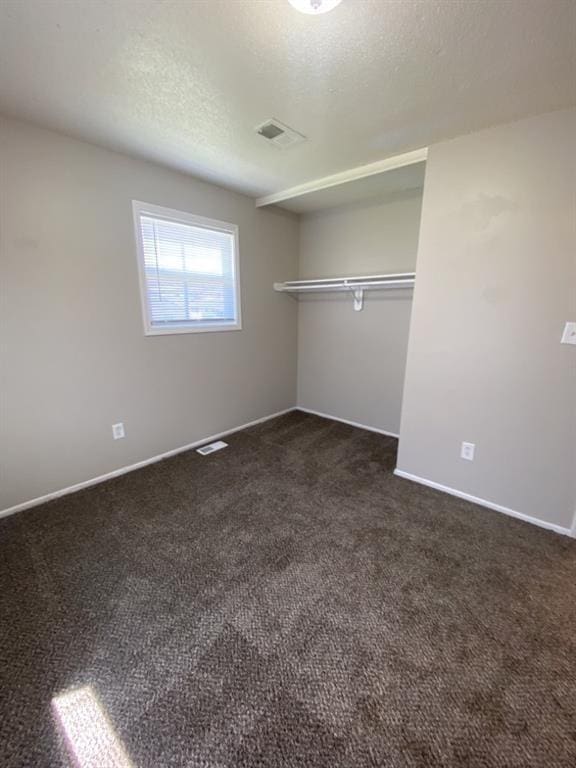 18822 E Wigwam Dr, Independence, MO 64056 - unfurnished bedroom with visible vents, baseboards, a textured ceiling, and dark carpet