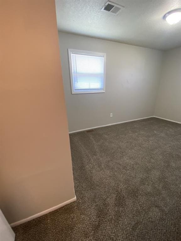 18822 E Wigwam Dr, Independence, MO 64056 - empty room with visible vents, baseboards, a textured ceiling, and dark carpet