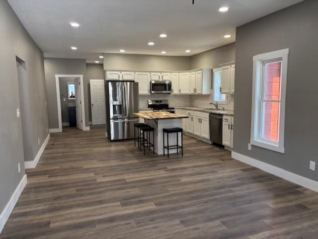 kitchen with stainless steel appliances, baseboards, tasteful backsplash, and white cabinets