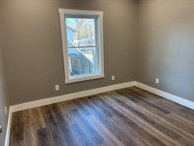 unfurnished room featuring baseboards and dark wood-style flooring