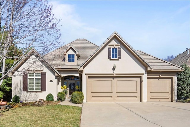 view of front facade with stucco siding, a front lawn, a tile roof, concrete driveway, and an attached garage