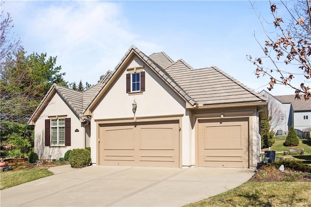 view of front facade with a garage, stucco siding, driveway, and a tiled roof