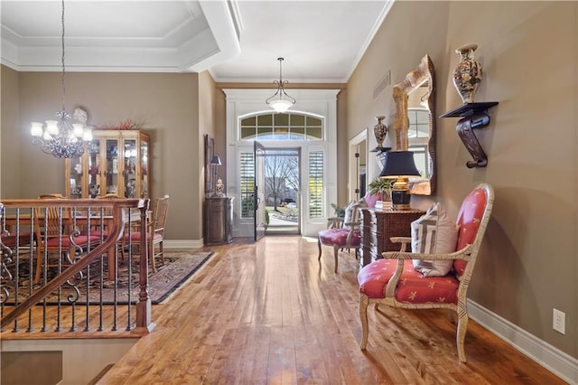 foyer entrance with baseboards, a notable chandelier, hardwood / wood-style floors, and crown molding