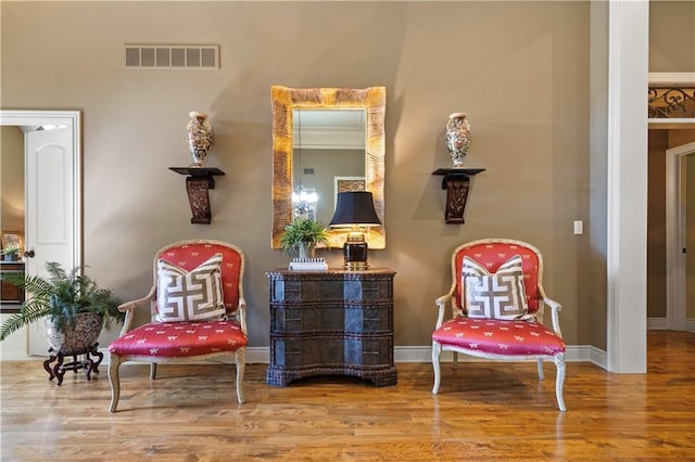 sitting room with wood finished floors, visible vents, and baseboards