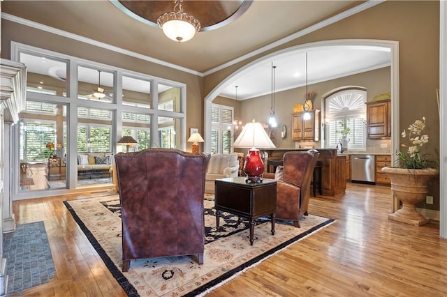 living room featuring arched walkways, light wood finished floors, and ornamental molding