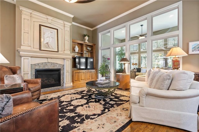 living area featuring a premium fireplace, wood finished floors, ceiling fan, and ornamental molding