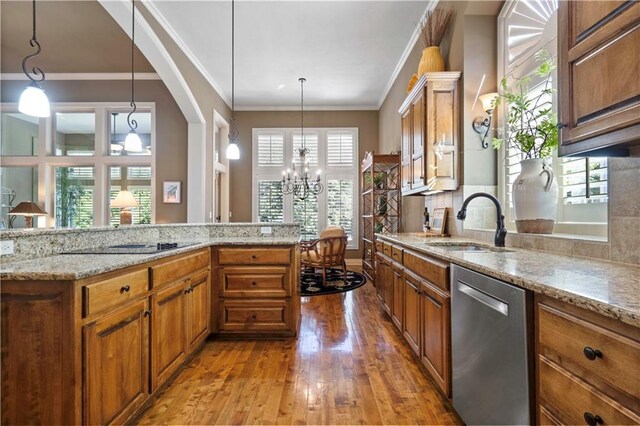 kitchen featuring light stone counters, brown cabinets, stainless steel dishwasher, light wood-style floors, and a sink