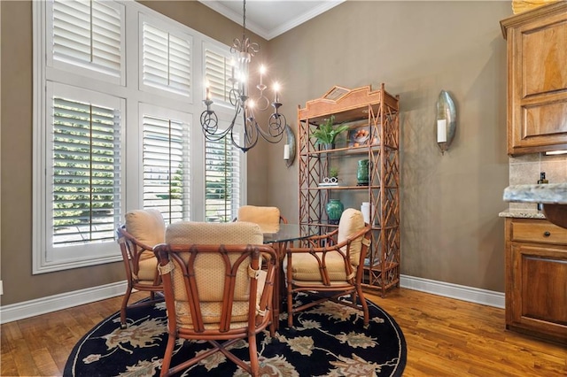 dining room featuring baseboards, wood finished floors, an inviting chandelier, and ornamental molding