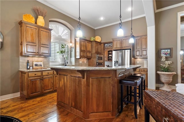 kitchen with a breakfast bar, crown molding, brown cabinetry, and stainless steel appliances