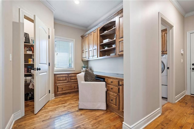 office with crown molding, baseboards, built in desk, light wood-style flooring, and washer / clothes dryer