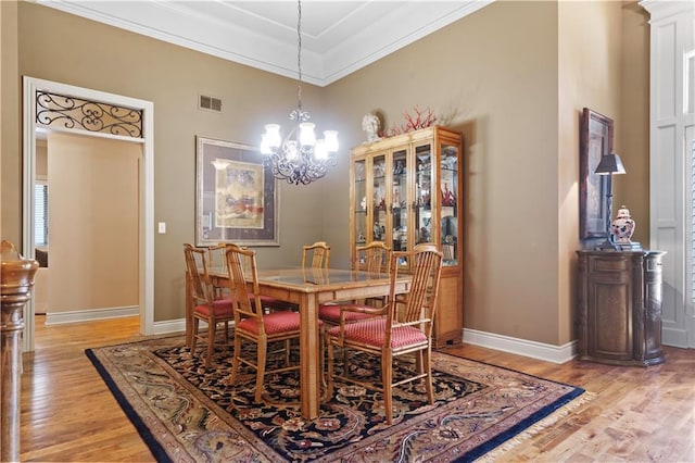 dining space with an inviting chandelier, light wood-type flooring, visible vents, and ornamental molding