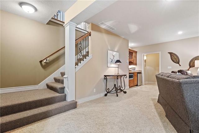 living area featuring visible vents, light carpet, baseboards, and stairs