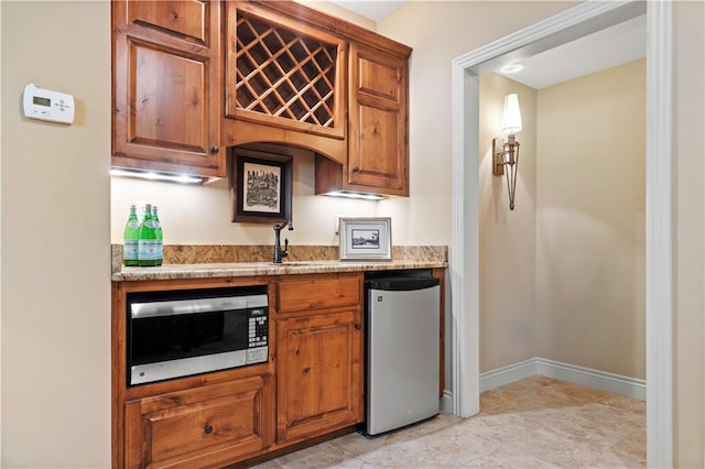 kitchen featuring stainless steel microwave, brown cabinets, and refrigerator