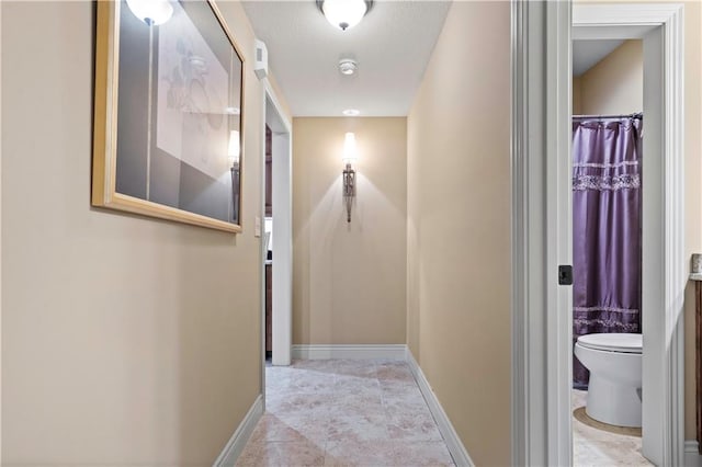 hall with a textured ceiling and baseboards