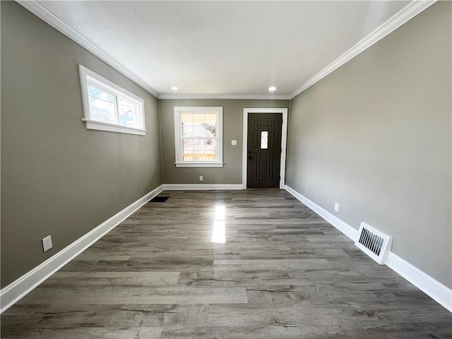 foyer with visible vents, crown molding, and baseboards