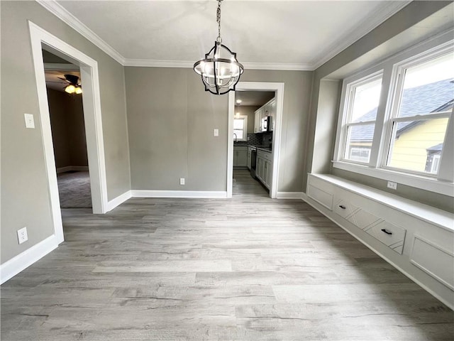 unfurnished dining area featuring baseboards, wood finished floors, a healthy amount of sunlight, and ornamental molding