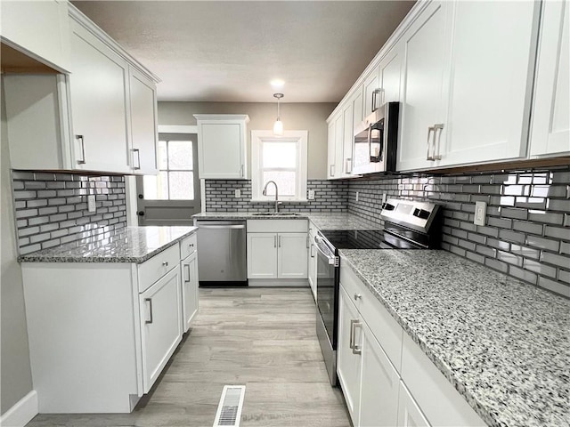 kitchen featuring a sink, stainless steel appliances, visible vents, and white cabinetry