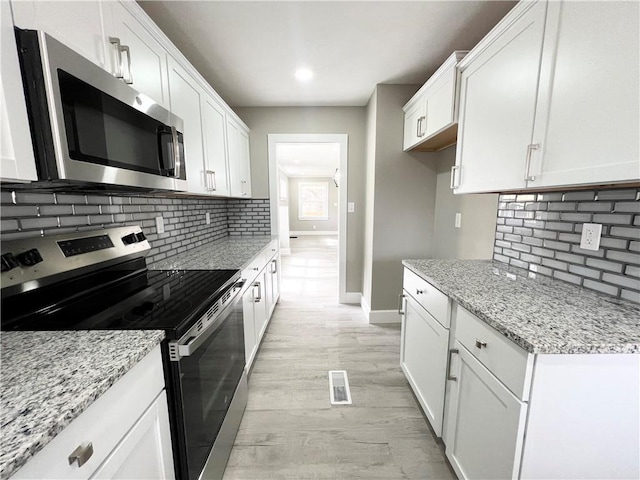 kitchen with white cabinets, light wood-style floors, visible vents, and stainless steel appliances