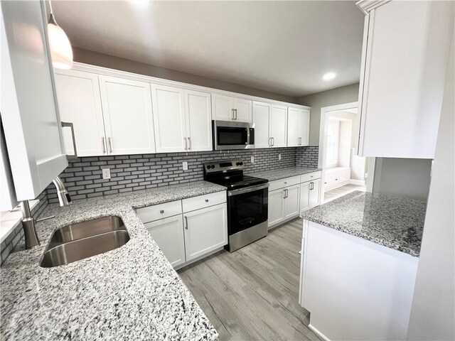 kitchen featuring backsplash, white cabinets, appliances with stainless steel finishes, and a sink