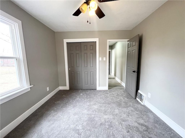 unfurnished bedroom featuring a ceiling fan, visible vents, baseboards, carpet floors, and a closet