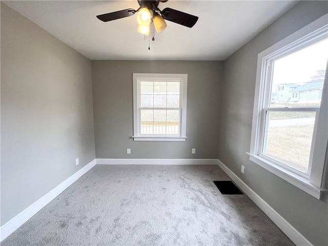 carpeted spare room featuring visible vents, baseboards, and ceiling fan