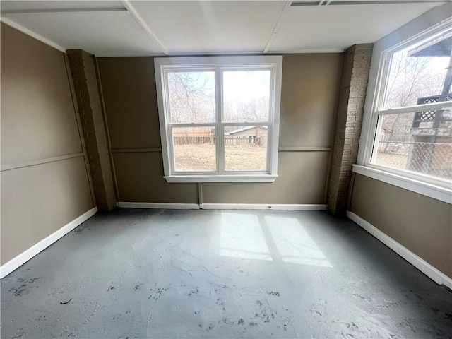 unfurnished room featuring baseboards, concrete floors, and a healthy amount of sunlight