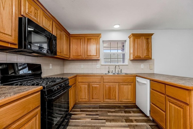 kitchen featuring dark wood-style floors, a sink, black appliances, brown cabinets, and backsplash