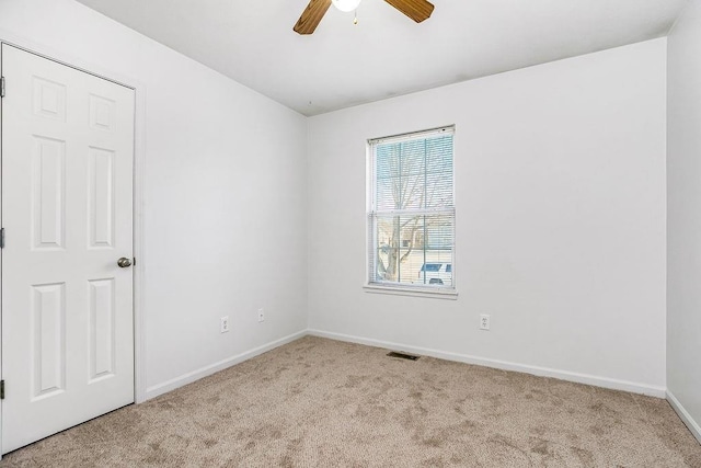 carpeted empty room featuring visible vents, baseboards, and ceiling fan