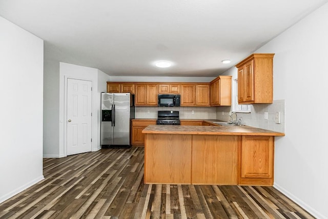 kitchen with black appliances, dark wood-style flooring, backsplash, and a sink