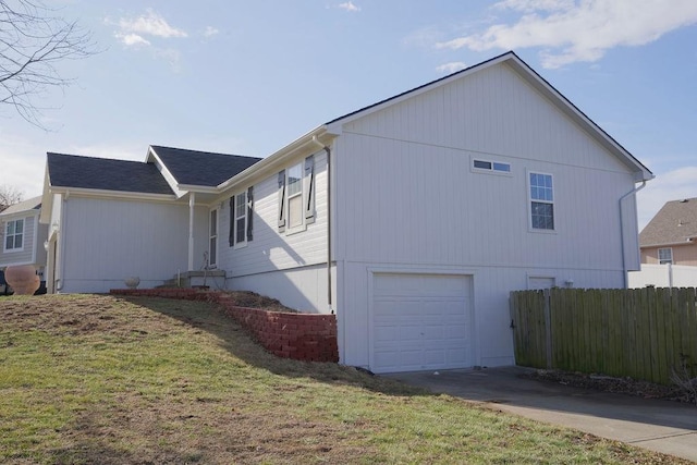 view of side of property with a yard, driveway, an attached garage, and fence