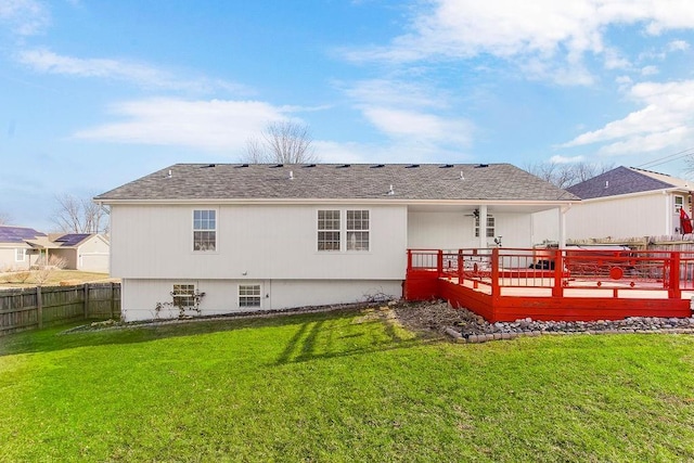 back of house featuring a wooden deck, a lawn, a shingled roof, and fence