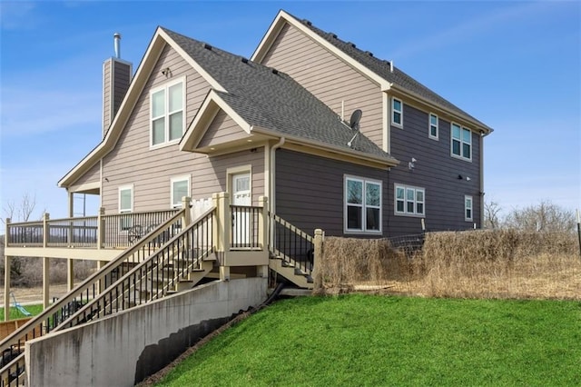 back of house featuring a shingled roof, stairway, a lawn, and a chimney