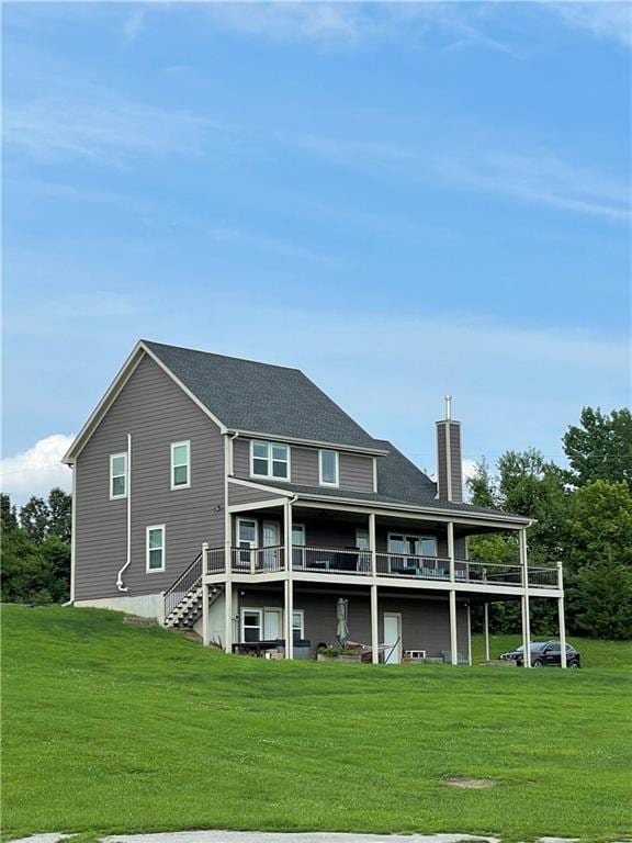 rear view of house with a deck, a yard, stairs, and a chimney