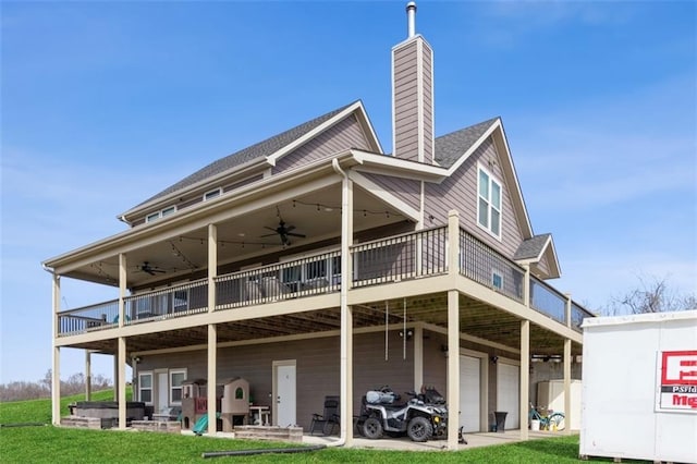 back of house featuring a garage, a lawn, a chimney, and ceiling fan