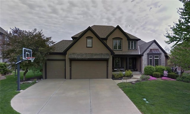 tudor house with a front lawn, an attached garage, driveway, and stucco siding