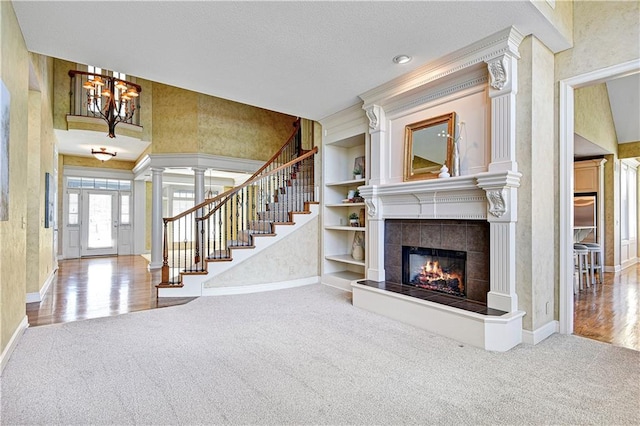 living room featuring built in features, decorative columns, a fireplace, and carpet flooring