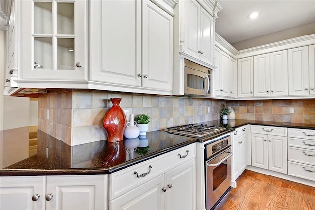 kitchen with stainless steel appliances, light wood finished floors, backsplash, and white cabinetry