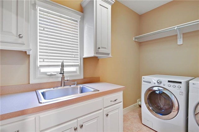 clothes washing area with light tile patterned floors, baseboards, cabinet space, a sink, and washing machine and dryer