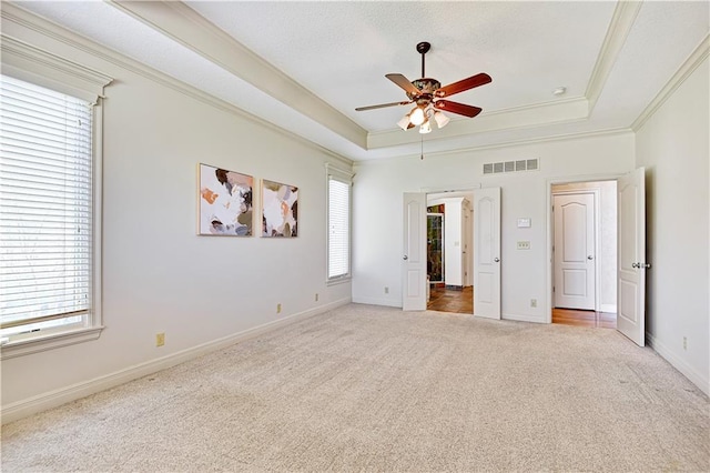 unfurnished bedroom featuring visible vents, a raised ceiling, carpet floors, and ornamental molding