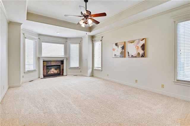 unfurnished living room with a raised ceiling, carpet floors, crown molding, baseboards, and ceiling fan