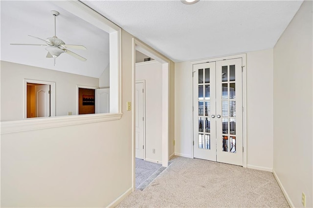 hallway with french doors, baseboards, carpet floors, and a textured ceiling