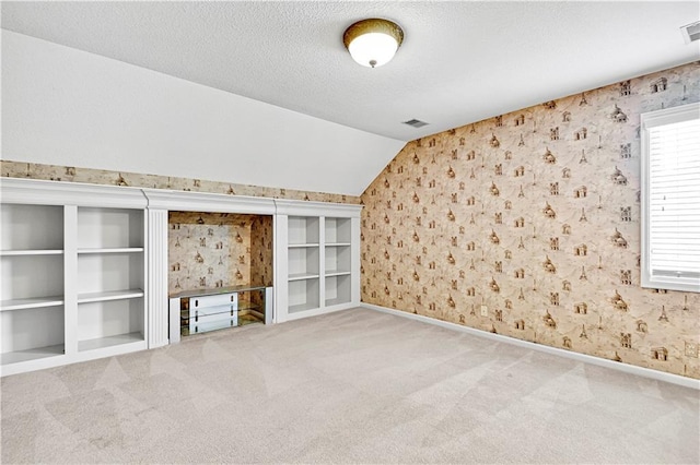 unfurnished living room featuring wallpapered walls, lofted ceiling, carpet flooring, and a textured ceiling