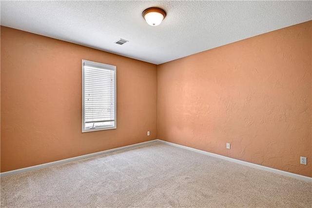 unfurnished room featuring visible vents, baseboards, carpet floors, a textured wall, and a textured ceiling