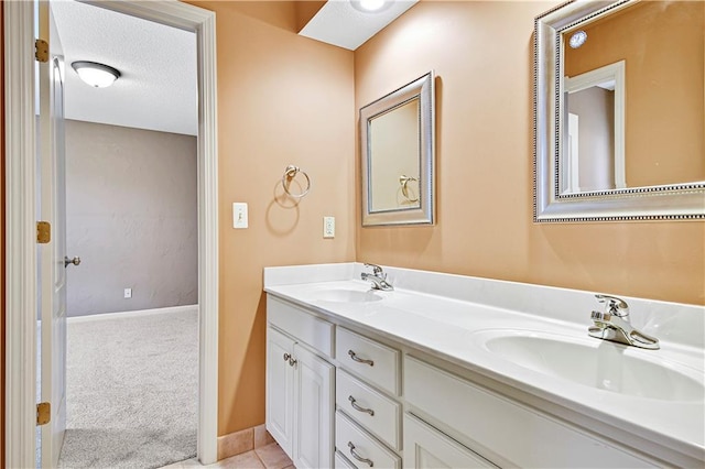 bathroom featuring a sink, baseboards, a textured ceiling, and double vanity